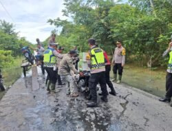 Banjir Merendam Jalan, Polisi Bantu Warga Seberangkan Motor.