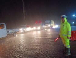 Ditengah Hujan Deras dan Genangan Air, Personel Unit Lantas Polsek Negara Atur Arus Lalulintas 