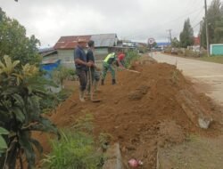 Babinsa Koramil 07/Atu Lintang Bantu Warga Timbun Jalan Menuju Kantor Desa Merah Mege